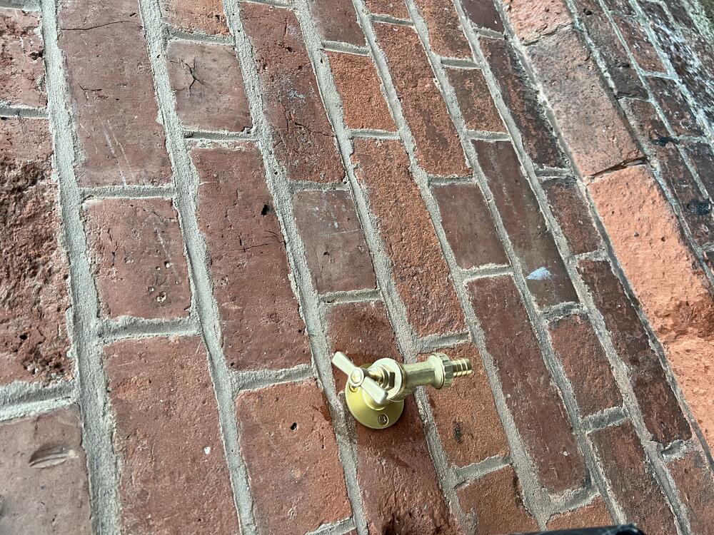 New outdoor brass tap fitted to a brick wall
